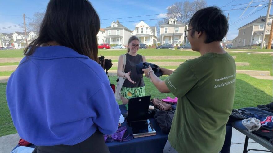 Zay Min Htike, founder of UD's clothing swaps initiative, gives clothing to a student who found an item at the swap. Before the handoff, team members weigh each item. They also document how many students participate.