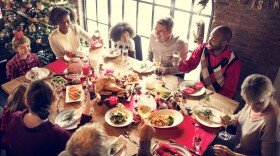 A photo of a family gathered around a table in festive Christmas wear.