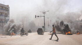 A man crosses through burning barricades in the central avenues in Ouagadougou where group of young demonstrators supporting the role of the army protested against President Marc Christian Kabore.
