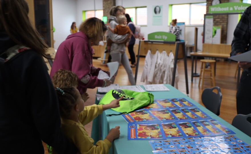 Families selecting activity books themed with Daniel Tiger from the PBS KIDS® show Daniel Tiger’s Neighborhood from WKAR