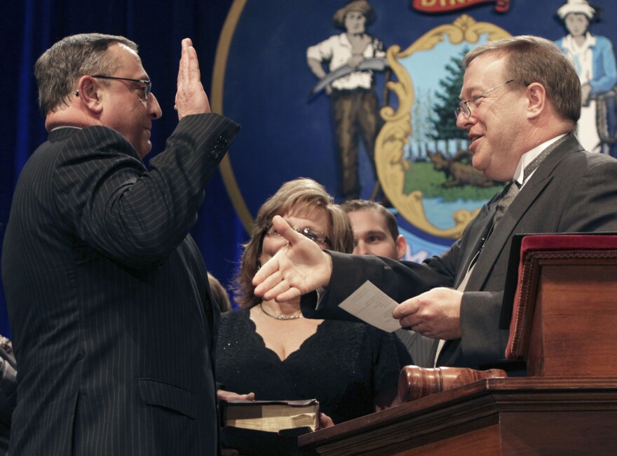 Republican Paul LePage, left, holds his hand on a Bible as Senate President Kevin Raye, right, reaches to congratulate him after administering the oath of office while being sworn in as Maine's next governor on Wednesday, Jan. 5, 2011, in Augusta, Maine.