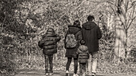 Black and white image of family walking on a trail with their coats on and it looks like the weather is chilly or cold.