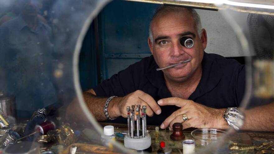 LOOKING FOR THE U.S.: A private Cuban watch repair shop owner peers out of his business in Havana.