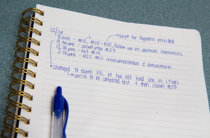 A photo of notes on a pad with the times 8 a.m., 9:30 a.m., 12:00 p.m. and 2 p.m. indicating different abbreviations for dental procedures.