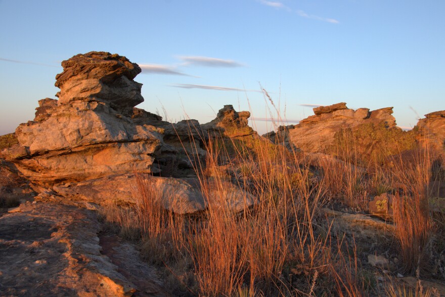 Orange and pink light streams over Black Mesa State Park as the sun rises over the Rock Garden Trail.