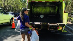 A woman tosses bags of trash into a garbage truck during a Great American Clean Up event.