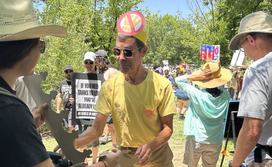A rallygoer picks up a king hat in Mariposa Basin Park, Albuquerque, on a day of nationwide 'No Kings' protests, June 14, 2025.