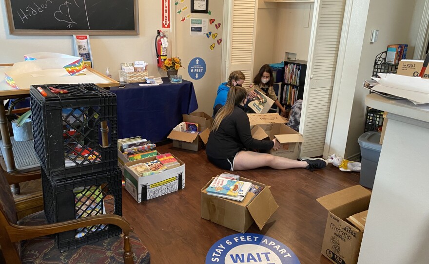 Madison Knefley and some fellow scouts sort through boxes filled with books and organize them on shelves in the community room at a Lake Highlands public housing complex. 