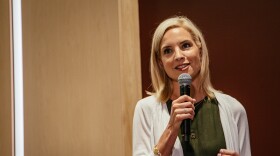 A blond woman speaks into a microphone.