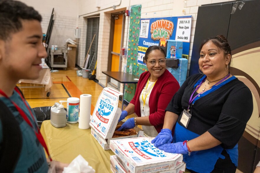 Carmen Mendoza, center, volunteers to serve lunch to students and staff at the summer camp.