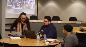 Anchorage School Board members huddle around a computer discussing budget cuts during a work session on Dec. 7, 2024.