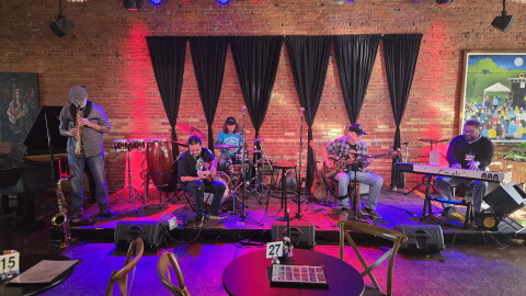 musicians on stage at UrbanBeat including a guitar player, a bass player, a piano player, a soporano saxophone player and a drummer.