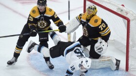 Utah Hockey Club center Alexander Kerfoot (15) tumbles in front of Boston Bruins defenseman Brandon Carlo (25) and goaltender Joonas Korpisalo (70) in the second period of an NHL hockey game, Thursday, Nov. 21, 2024, in Boston. (AP Photo/Steven Senne)