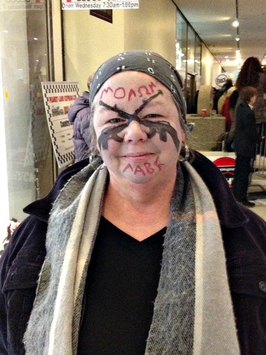 Woman with her face painted white with two black bushmaster riffels crossed across her nose