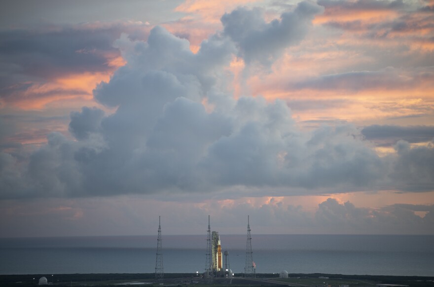 A cloudy sunrise over a rocket on a launchpad.