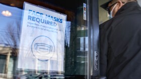 A customer enters a restaurant past a sign posted to the door requiring masks Wednesday, Feb. 9, 2022, in Providence, R.I. As the omicron wave of the coronavirus subsides, several U.S. states including New York and Illinois ended mask mandates this week for indoor settings, while others lifted requirements at schools. (AP Photo/David Goldman)