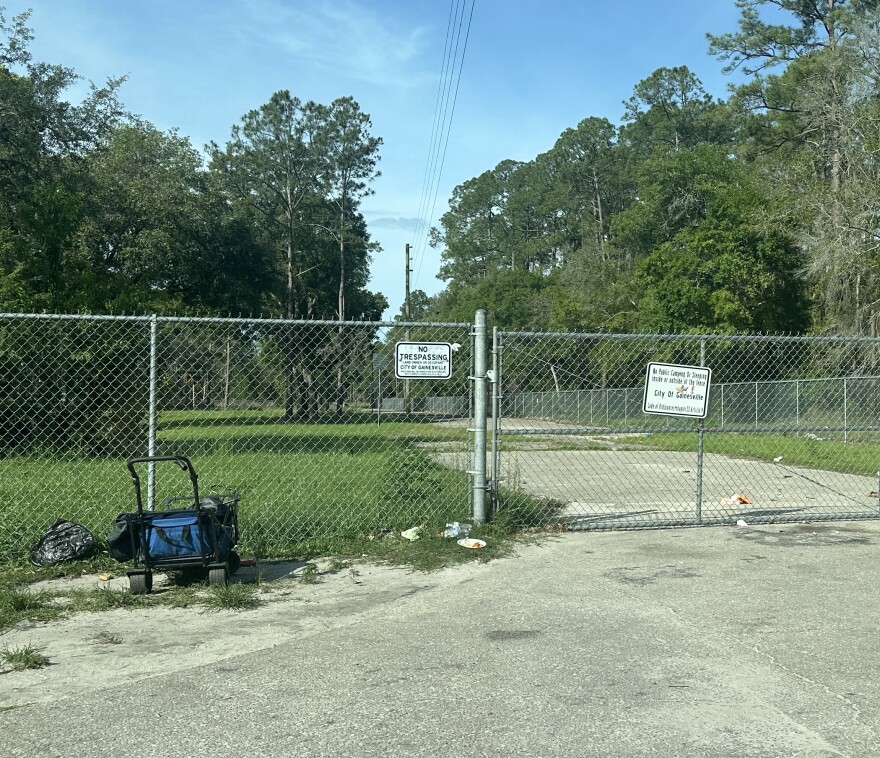 'No trespassing' and 'No public camping' signs on a fence in Gainesville.