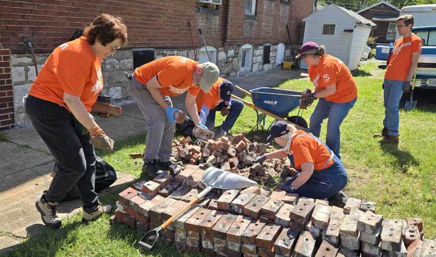 Volunteers from international relief organization Samaritan's Purse organize and clean up bricks on Friday, May 23, 2025 that were blown from the roof of an apartment building on N. Sarah St. in St. Louis city's Ville neighborhood. The building was damaged by an EF3 tornado that left five people dead and dozens injured on May 16 in the St. Louis region.