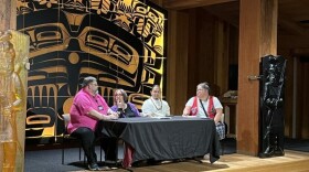 four people sit at a table, on a stage