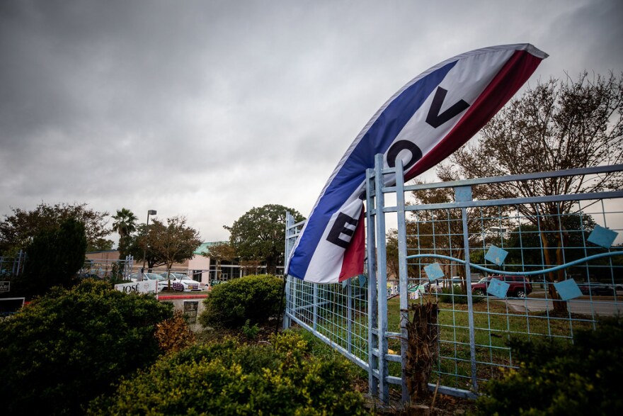 A "Vote" sign, bent over by stormy weather, outside a polling place