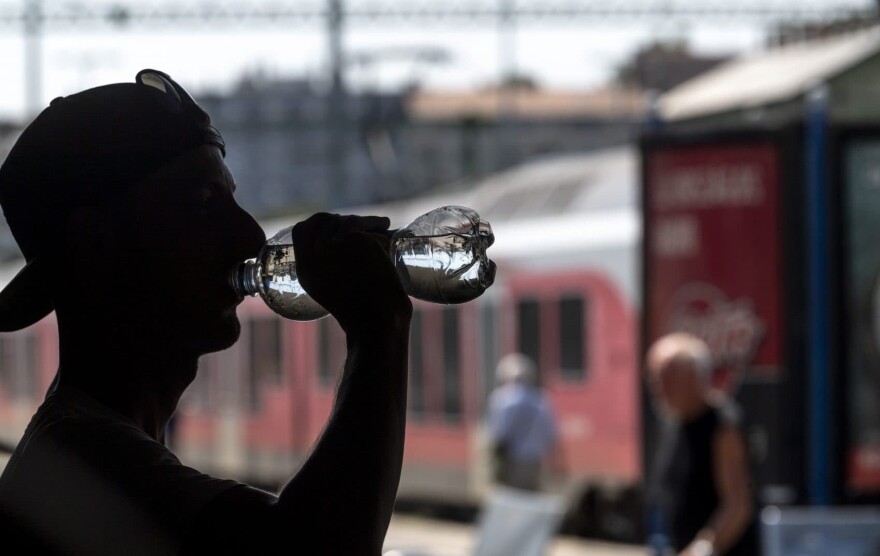A man drinks water distributed free to passengers of the Hungarian State Railways at the Deli Railway Station in Budapest, Hungary, Monday, July 30, 2018, as the highest daytime temperature may reach 35 degrees Celsius (95 degrees Fahrenheit) in most parts of the country, and the highest degree heat alert has been issued by the Hungarian health authority. (Zsolt Szigetvary/MTI via AP)