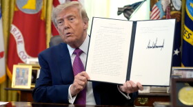President Donald Trump holds up a signed executive order in the Oval Office of the White House, Thursday, Aug. 27, 2026, in Washington.
