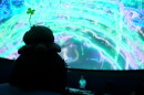 One of the attendees watches the DJ and the light show during the rave at the Challenger Center Fogg Planetarium.