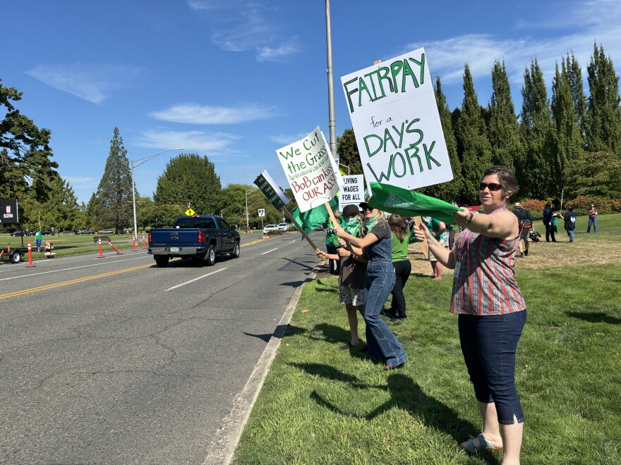 People hold signs and protest along the side of a road. 