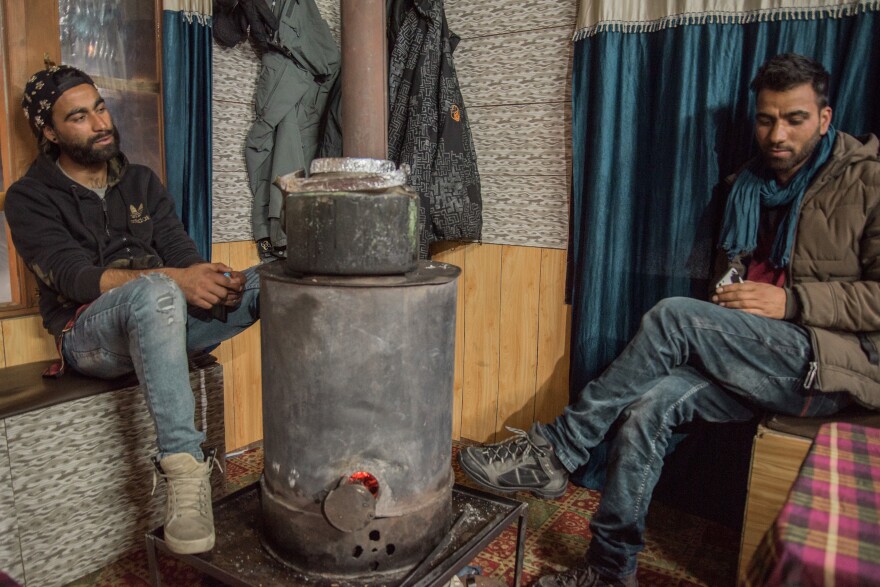 Raja Wasim Khan (left), 24, and his brother Ashraf Khan, 21, huddle around a wood stove inside the ski hut they manage in Gulmarg. The Khan brothers' father was a Kashmiri militant who served time in an Indian prison and then moved his sons to the mountains and taught them snowboarding. He wanted to keep them away from the violence he grew up in.