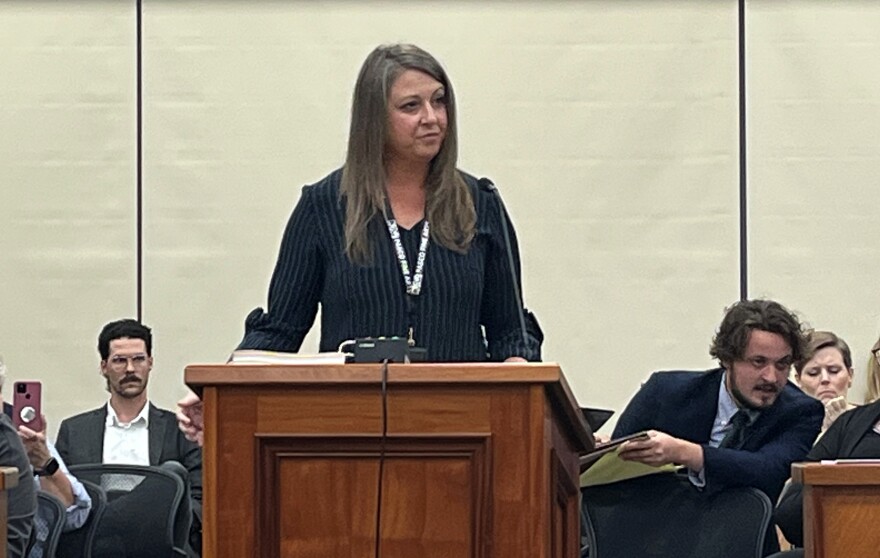 A woman in a navy blue top stands at a podium