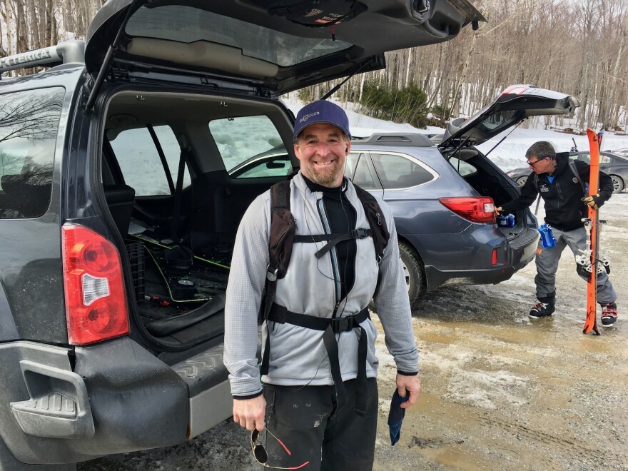 Two men get gear out of their cars in a parking lot.