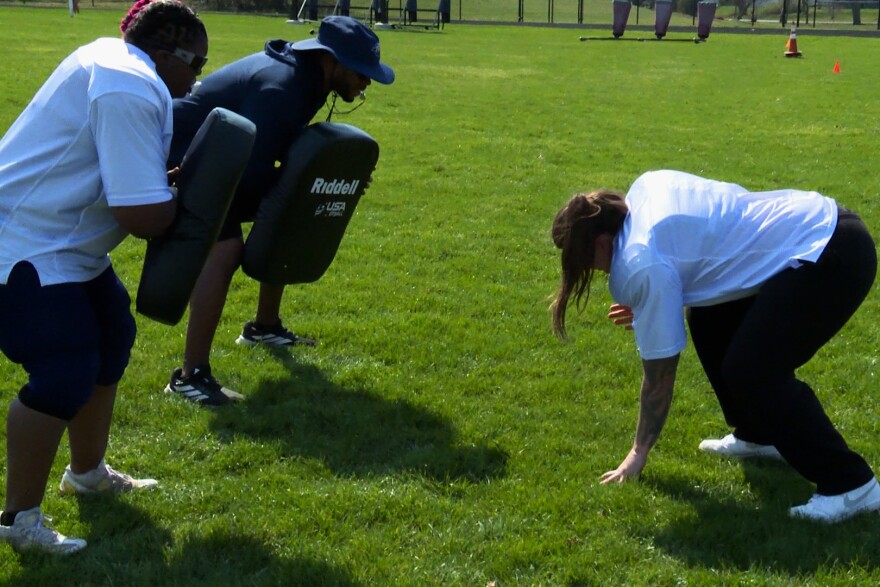 Two Indiana Valor players and a coach practice blocking. 
