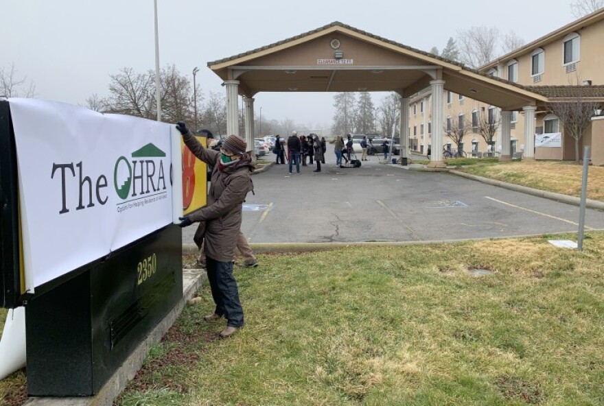 Pam Lott, Director of Administration for the non-profit Options for Helping Residents of Ashland, rolls up a banner covering the former Super 8 hotel in Ashland. It became the new home of a OHRA shelter starting in February.