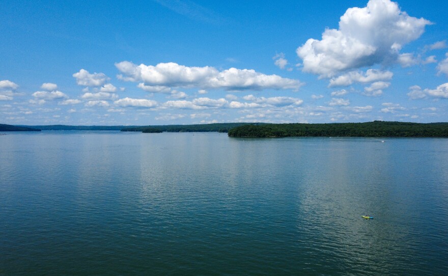 A kayaker floats on Lake Wallenpaupack under fluffy clouds.
