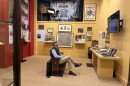 A man sits in a reproduced theatre seat in the middle of an exhibit on the early history of cinema at the Henry B. Plant Museum. 
