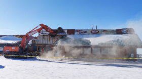 An excavator begins demolishing the IGA Food Cache building in Delta Junction Monday morning.