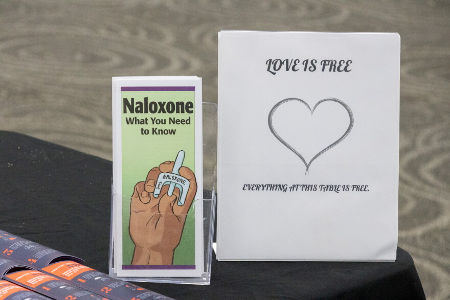 Pamphlet about Naloxene and a sign on West Texas Harm Reduction’s table reading “Love is free everything at this table is free”, photo by Alexander Brown.