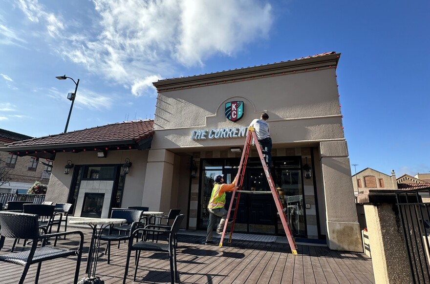 A crew from Reaching Solutions Sign Installation & Maintenance in Olathe installs signage for the Kansas City Current's new retail shop on the Country Club Plaza. The illuminated channel letter sign was fabricated by Midtown Signs in Kansas City, Kansas.