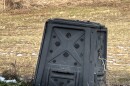 Crooked, broke-down compost bin with snow in foreground, field in background