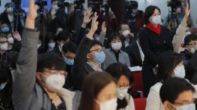 Reporters wearing medical masks raise hands to seek recognition at a Beijing press conference.