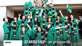 En la imagen se puede observar a  un grupo de estudiantes vestidos con batas y sombreros de graduacion color verse. En el lado inferior de la imagen esta el logo de Que Onda Michigan sobre un fondo blanco. En la parte derecha las siguientes palabras estan escritas: "El MSU Hep: un programa para trabajadores que buscan la equivalencia educacional."  y "Episodio 48". 