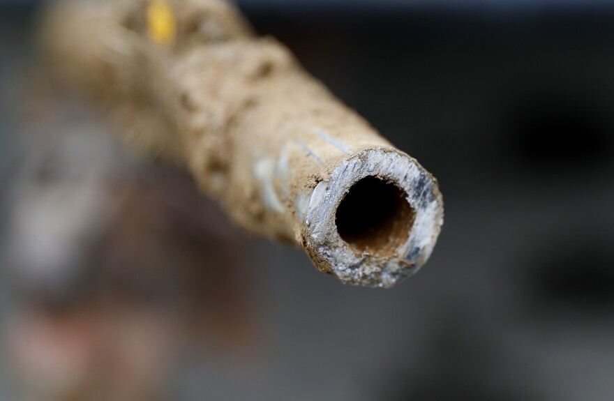 A close, three-quarter view of a narrow pipe, whose cut end faces just off-center. The pipe has dirt on its outside.