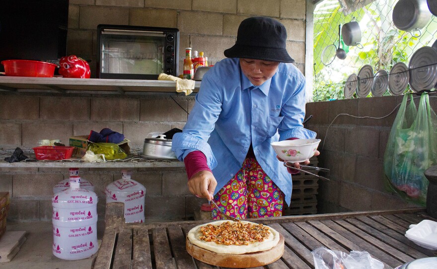 Nheb Thai's wife, Kim Lun, gets a pizza ready for the oven.