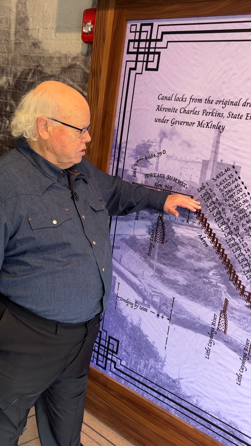 A man points to graphics on a wall that outline a canal system