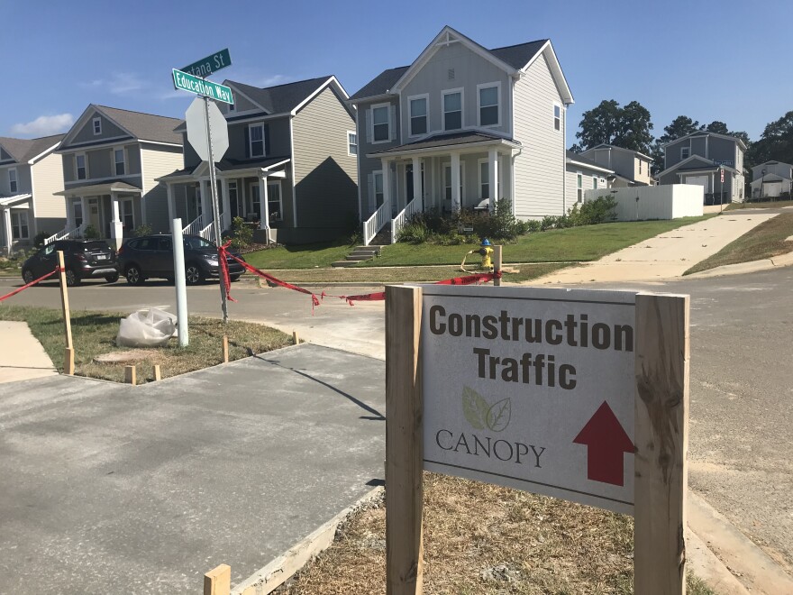 A sign that says "construction traffic" sits in front of a row of houses.