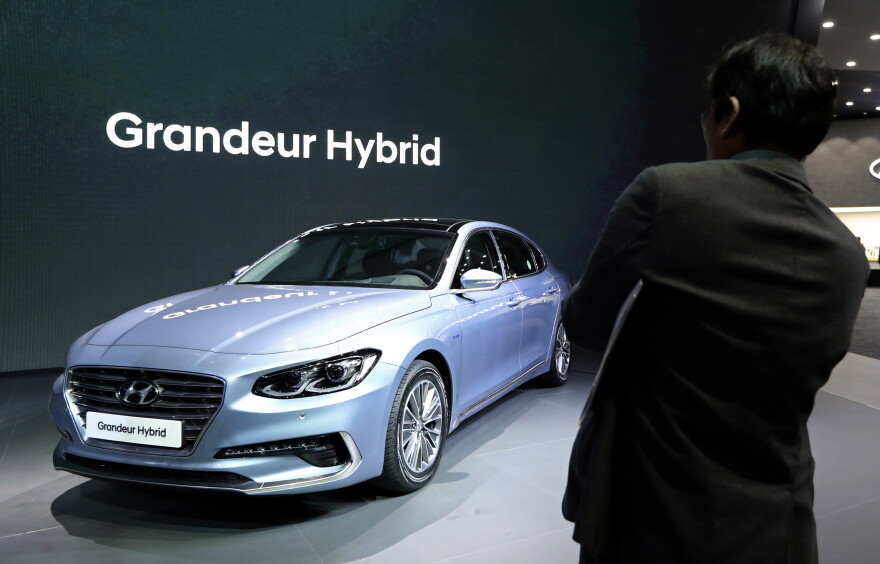 A man takes a photo of Hyundai Motor's Grandeur Hybrid vehicle during a media preview of the 2017 Seoul Motor Show in Goyang, South Korea, Thursday, March 30, 2017.