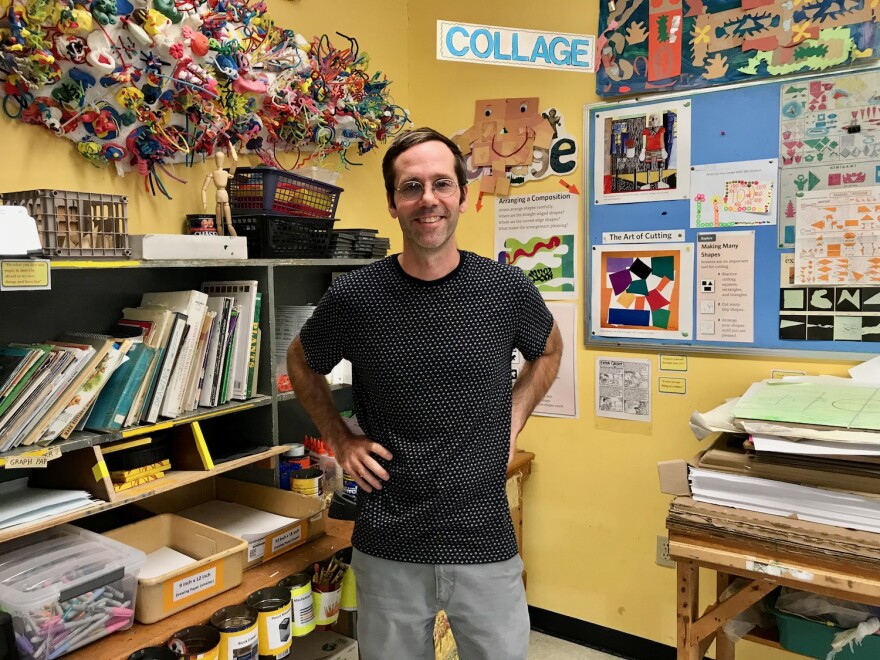 A man stands in front of school art supplies.