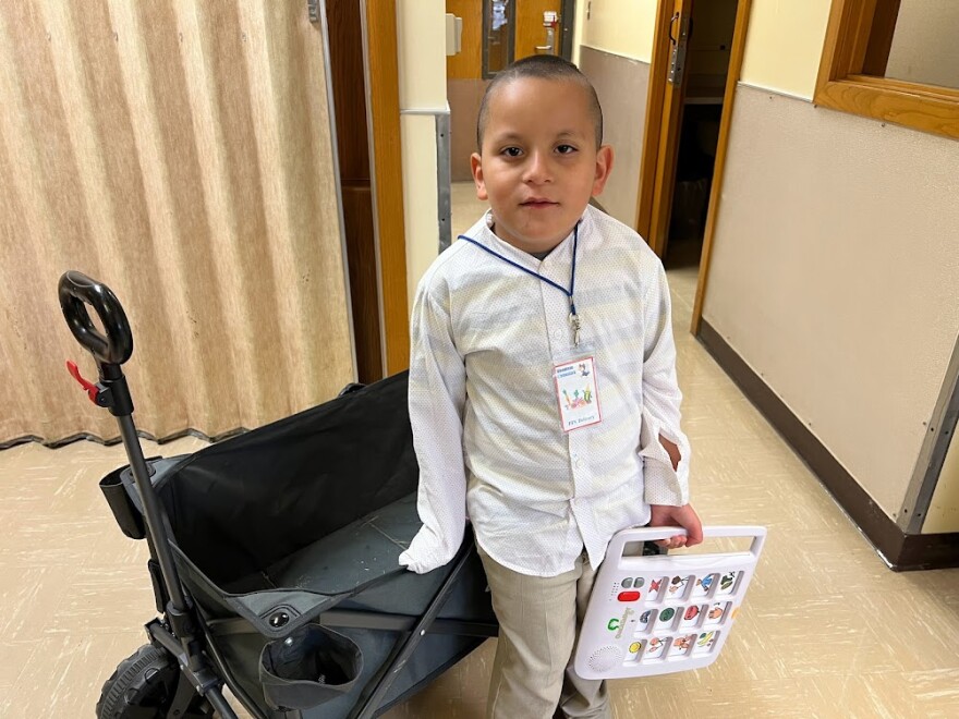 Jovany, a third-grader at Woodman Elementary School in Wichita, helps deliver fresh fruits and vegetables as part of the school's healthy-snack program. He uses a handheld speaking device to communicate with teachers and peers.
