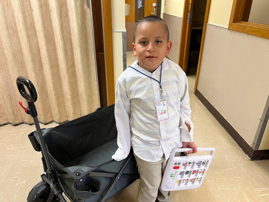  Jovany, a third-grader at Woodman Elementary School in Wichita, helps deliver fresh fruits and vegetables as part of the school's healthy-snack program. He uses a handheld speaking device to communicate with teachers and peers.