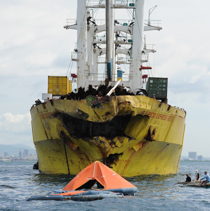 A life raft from the sunken ferry MV Thomas Aquinas floats in front of the cargo ship it collided with on Friday.